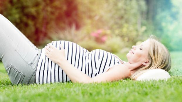 Schwangere liegt im Gras